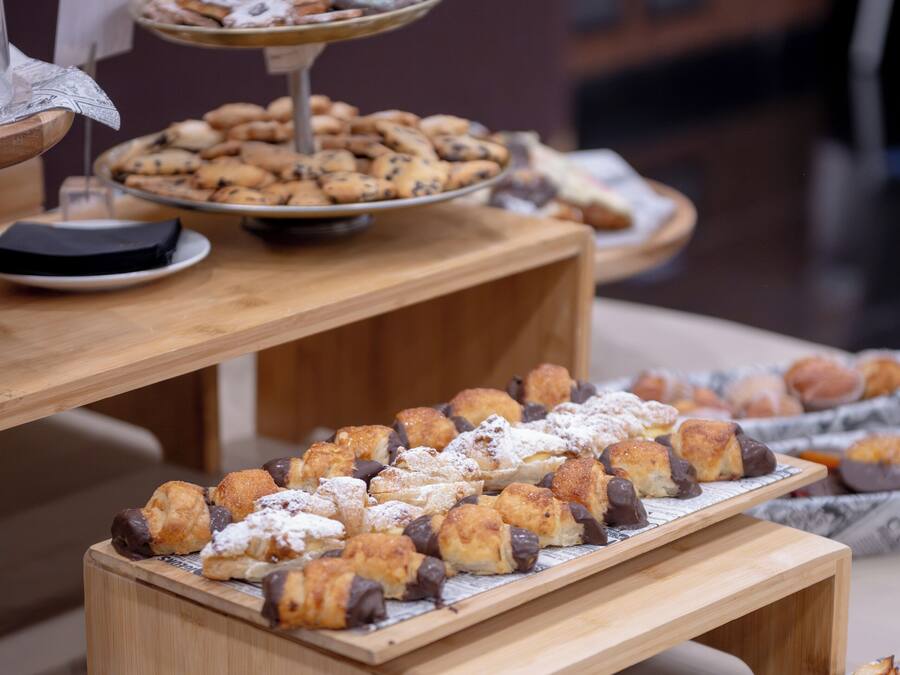 Een buffet met diverse gebakjes en desserts, gepresenteerd op houten presentatiestandaards.