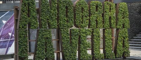Un cartel grande al aire libre con paneles verticales cubiertos de hiedra verde.