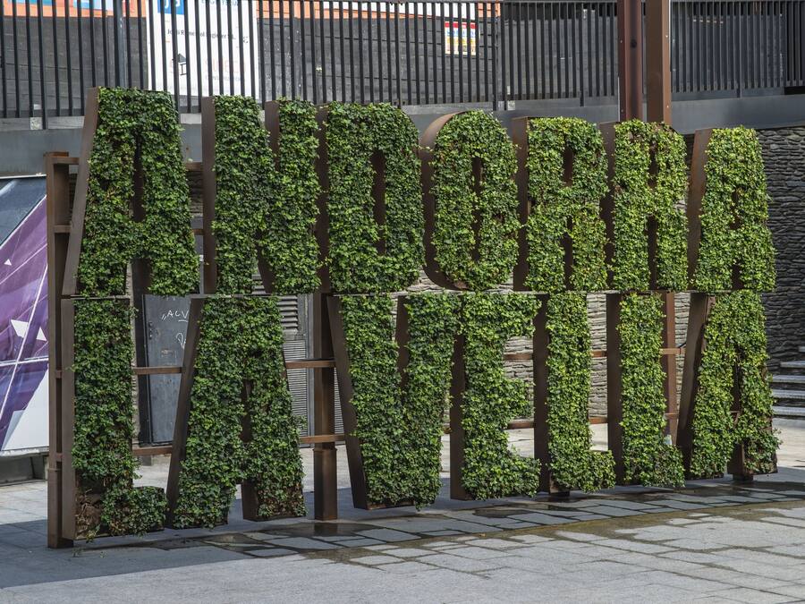 Un cartel grande al aire libre con paneles verticales cubiertos de hiedra verde.