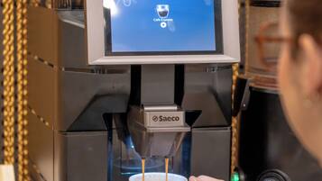 Una macchina per il caffè con un display digitale, una tazza e una persona che la tiene.