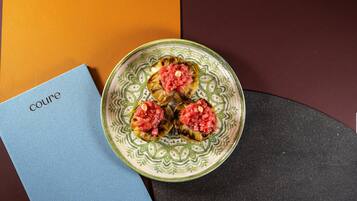 Une assiette décorative contenant trois champignons farcis, posée sur une table avec une serviette bleue et un livre intitulé « Cuisine » à côté.