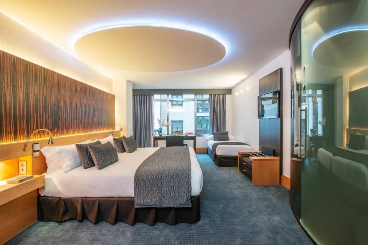 Une chambre d’hôtel moderne, dotée d’un grand lit, d’un bureau, d’une chaise et offrant une vue sur la ville.