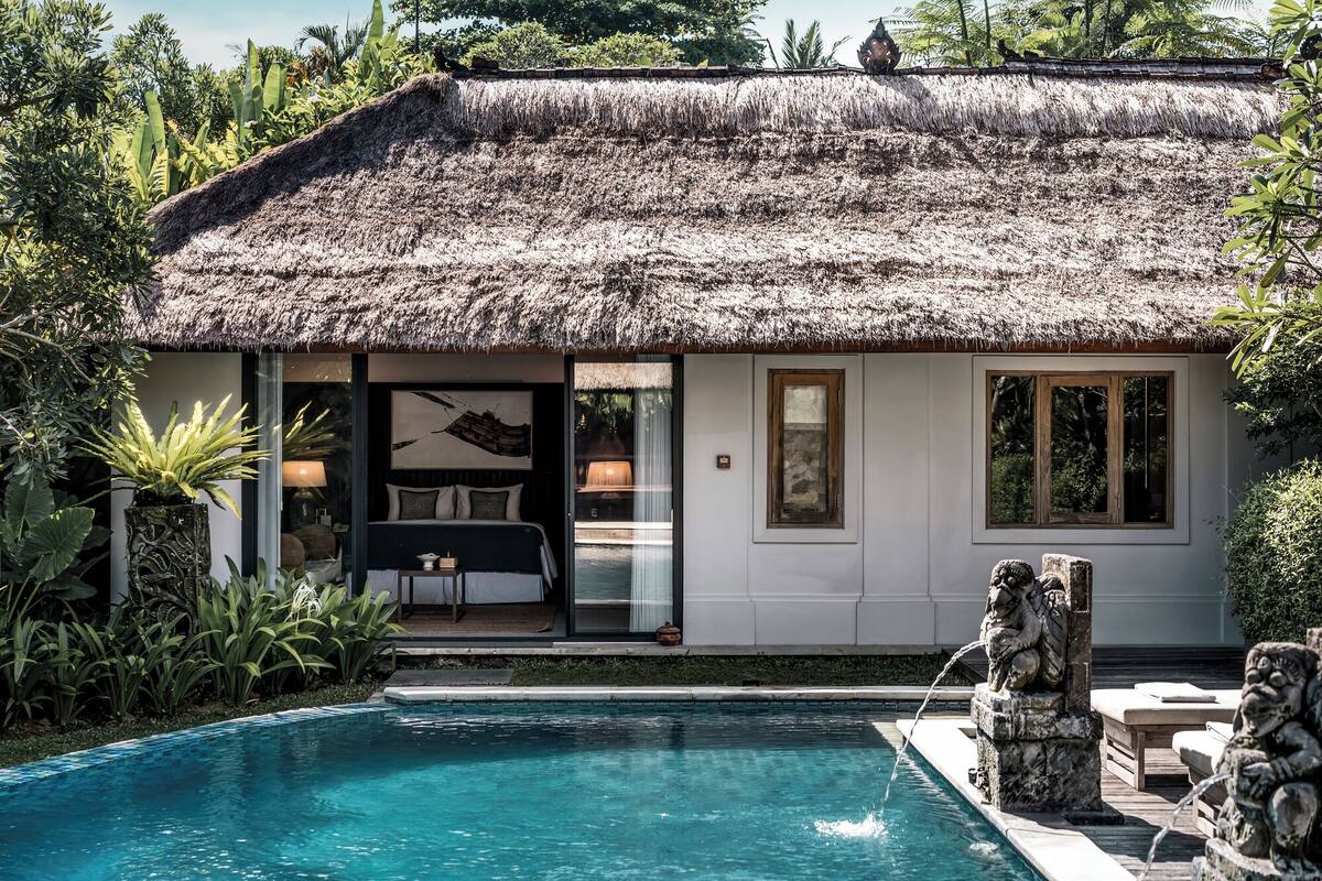 A thatched-roof building with a pool and a statue.
