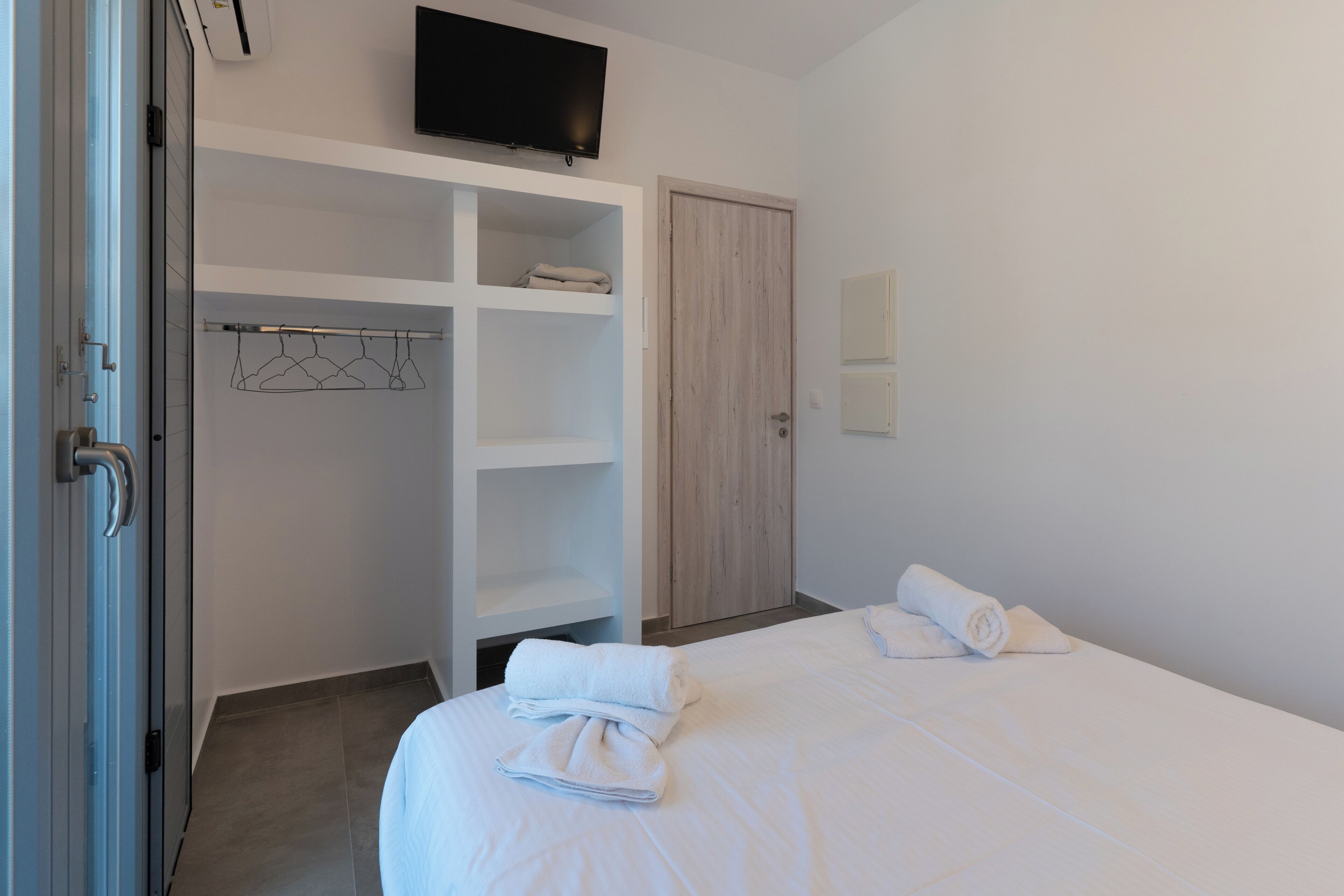 A hotel room with a bed, a wardrobe, a television, and a mirror.