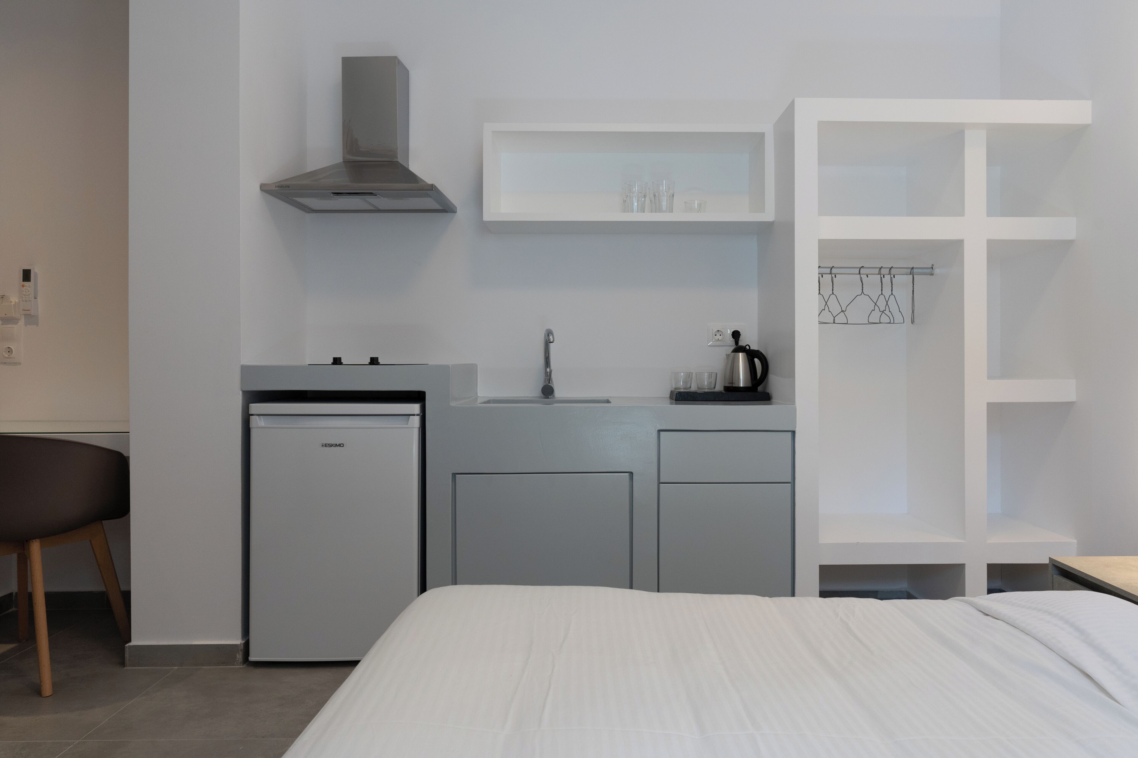 Une chambre d’hôtel compacte comprenant un lit, une kitchenette, un petit réfrigérateur, un évier et une armoire.