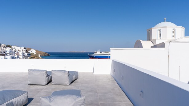 A rooftop terrace with white walls, a view of the sea, and a ship in the distance. - Bedspot Apartments Astypalaia (Astypalaia)