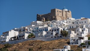 A coastal town with white buildings, a prominent castle-like structure on a hill, and a clear blue sky. - Bedspot Apartments Astypalaia (Astypalaia)