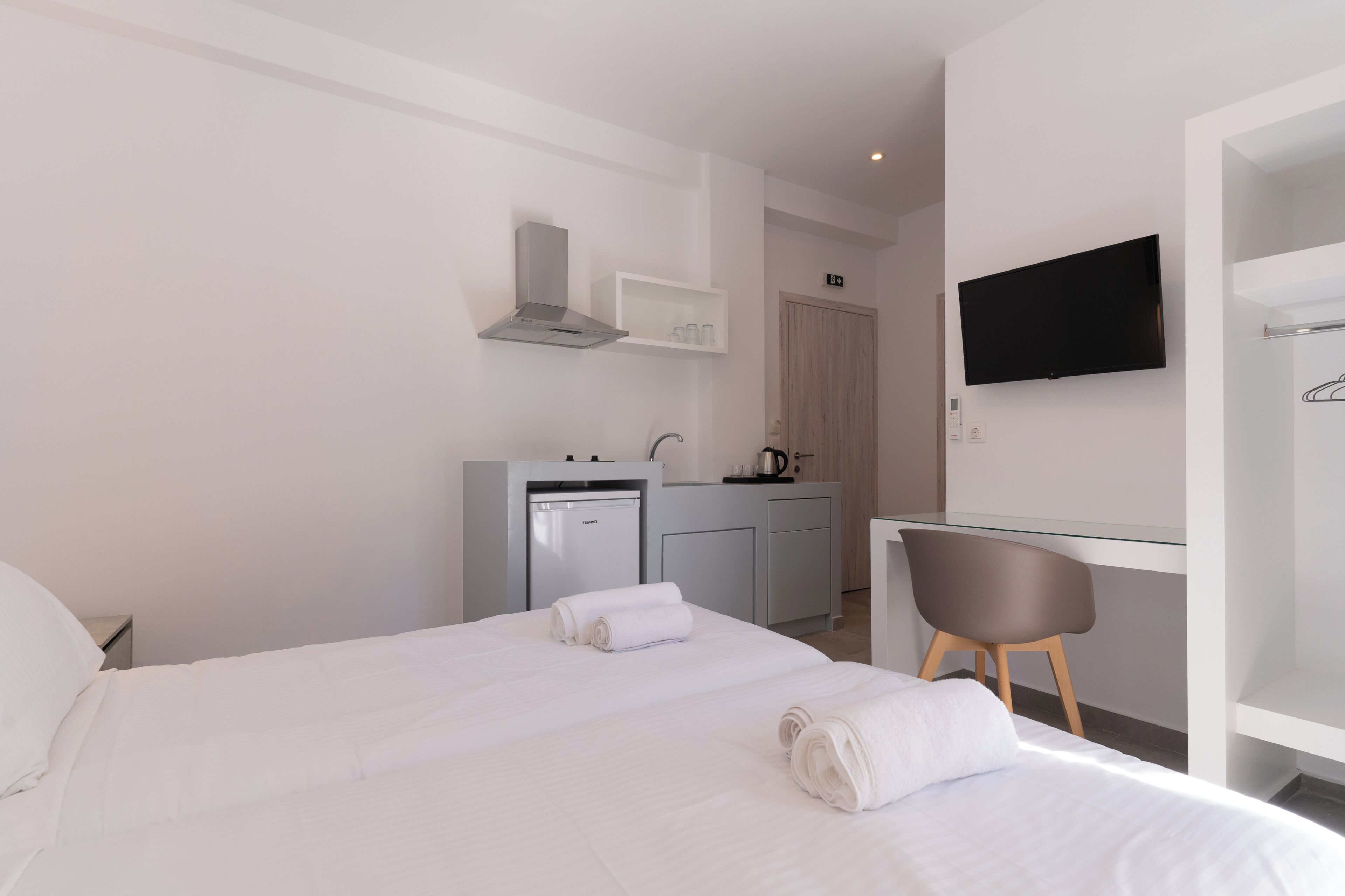 Une chambre d’hôtel équipée d’un lit, d’un bureau, d’une chaise, d’une télévision et d’une kitchenette.