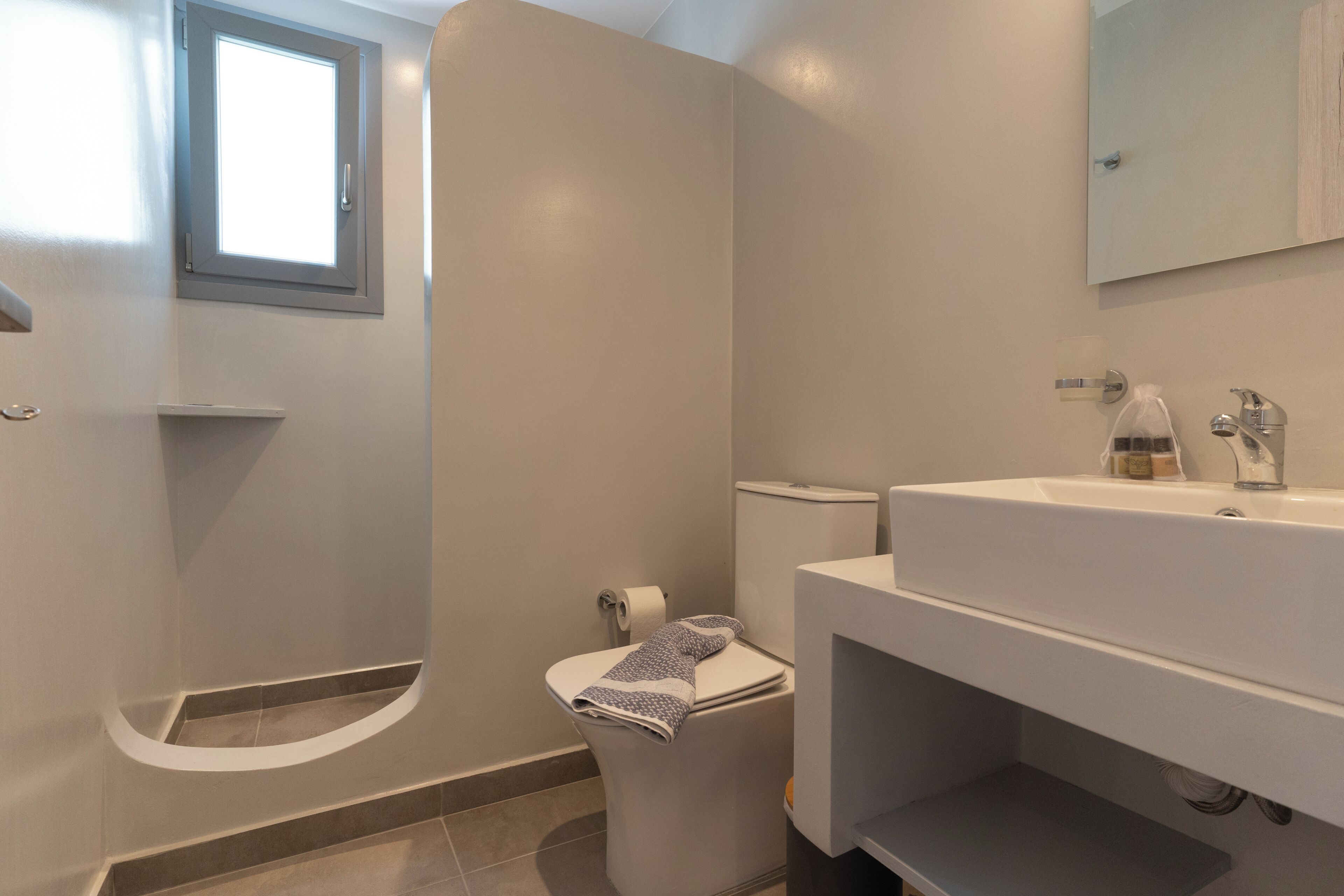 Un baño moderno con inodoro, lavamanos y ducha.