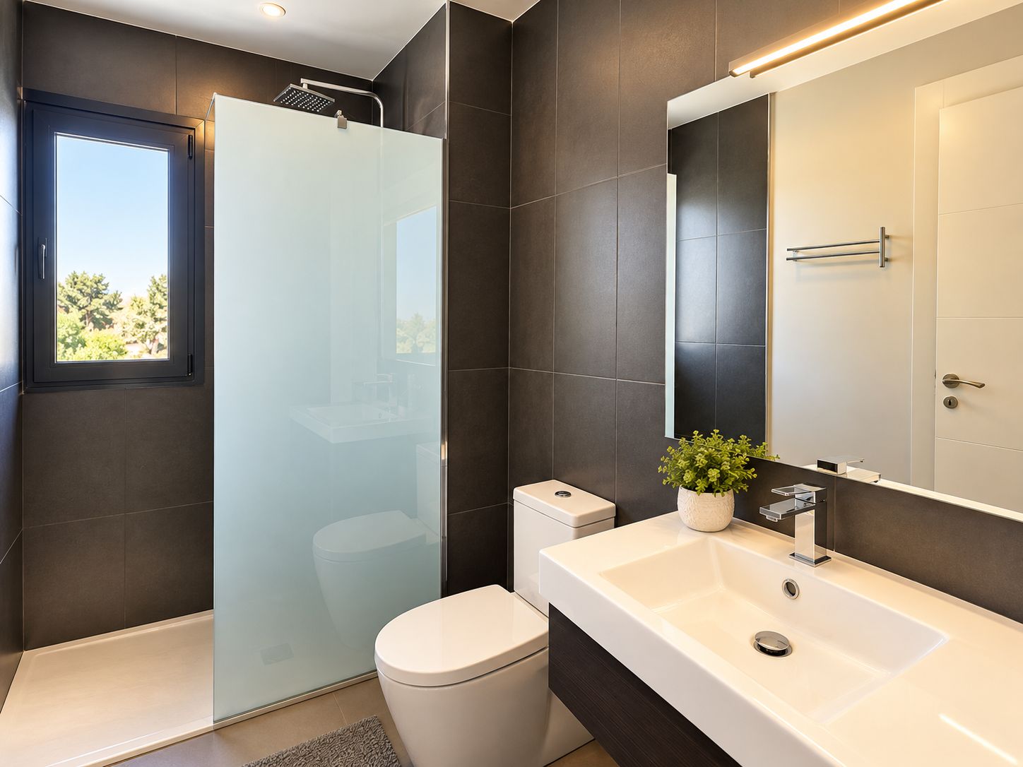 Ein modernes Badezimmer mit einer gläsernen Dusche, einer weißen Toilette und einem großen Spiegel über einem weißen Waschbecken.