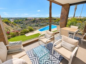 Ein Balkon mit Pool, Gartenmöbeln und Blick auf eine hügelige Landschaft.