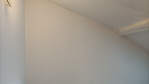 Ein schlichter Raum mit einem Einzelbett und einer schlichten weißen Decke.