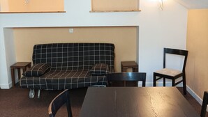 Ein Zimmer mit einem schwarz-weißen Karosobasofa, einem Holztisch und zwei Stühlen.