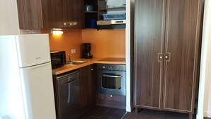 Eine kleine Küche mit Kühlschrank, Mikrowelle, Geschirrspüler, Backofen und Spüle.