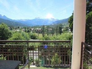 A balcony with a view of a mountainous landscape, a fence, and a table.