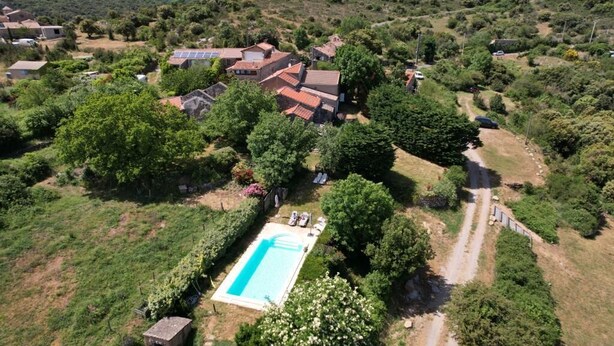Vue aérienne d’un quartier résidentiel avec des maisons, une piscine et de la végétation environnante.