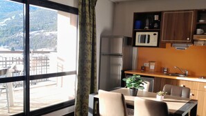 A modern kitchen with a refrigerator, microwave, and sink. There is a dining table with chairs and a potted plant. - Studio for 4 with terrace, pool and parking in Jausiers (Jausiers)