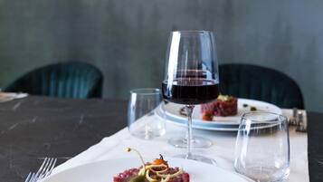 Una mesa de comedor con un plato de comida, una copa de vino tinto y un vaso de agua.