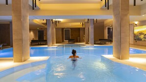A swimming pool with a person swimming, surrounded by pillars and benches. - Hotel Donna Vì (Geraci Siculo)