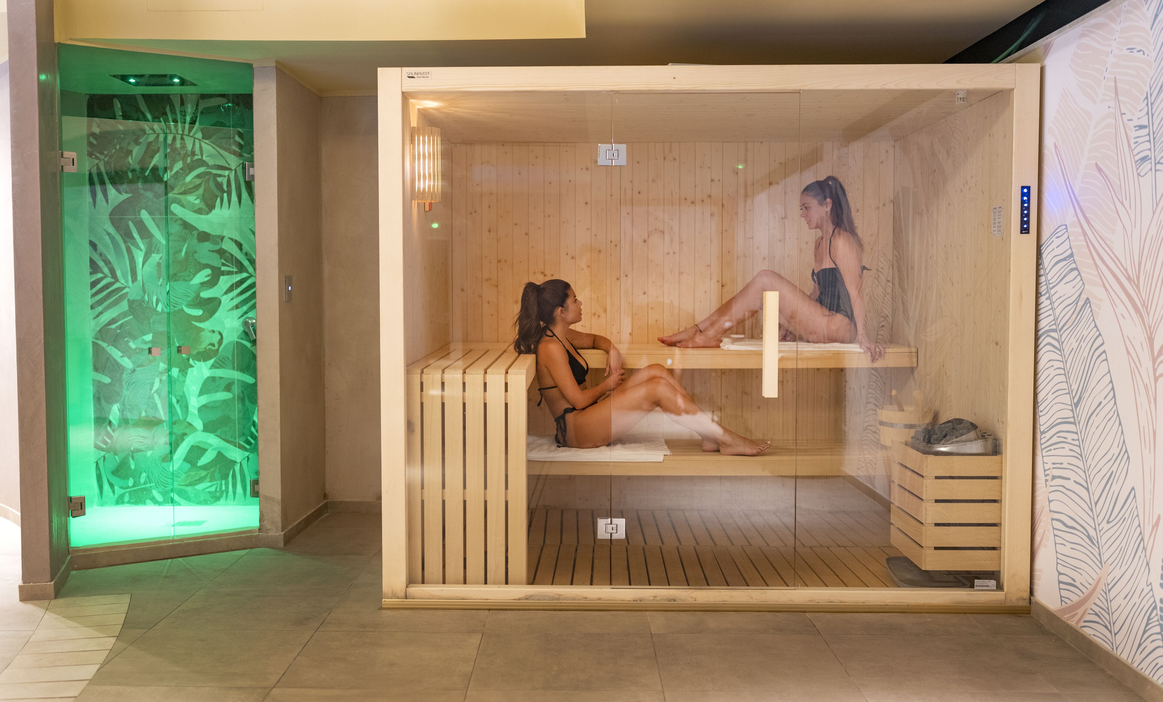A sauna with two wooden benches, a glass door, and a wooden floor.