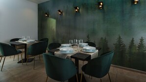 A dining area with a table set for six, surrounded by six chairs, and a mural of a forest on the wall. - Hotel Donna Vì (Geraci Siculo)