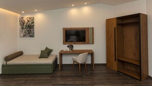 A compact room with a bed, a desk, a chair, a TV, and a wardrobe. - Hotel Donna Vì (Geraci Siculo)