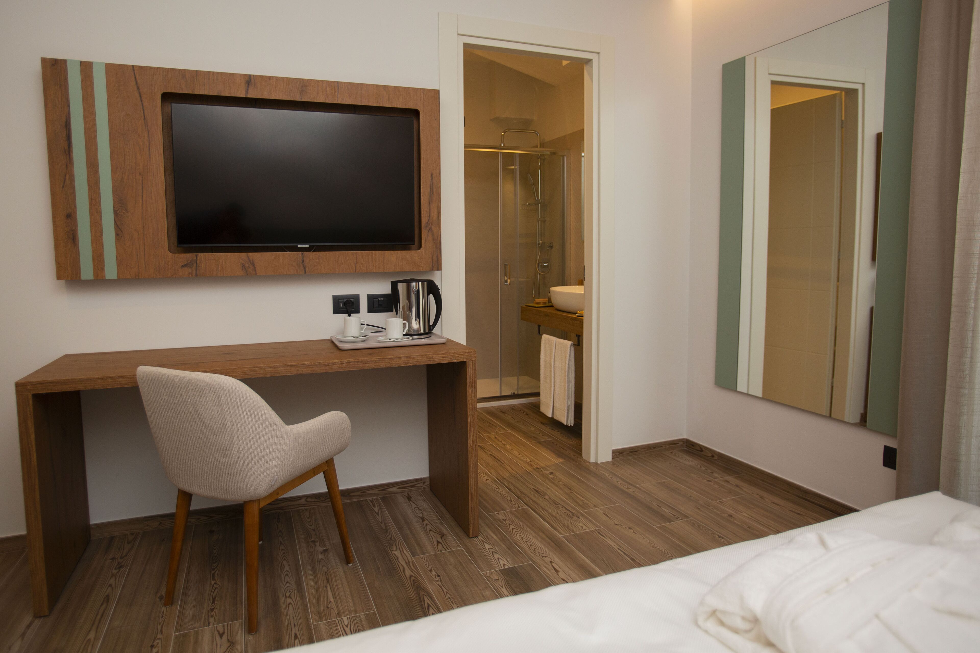 Una habitación de hotel con escritorio de madera, televisión, ducha y cama.