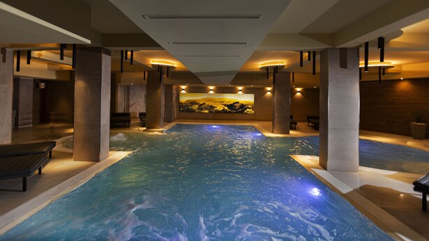 An indoor swimming pool with a large mural on the wall, benches, and a ceiling with recessed lighting. - Hotel Donna Vì (Geraci Siculo)