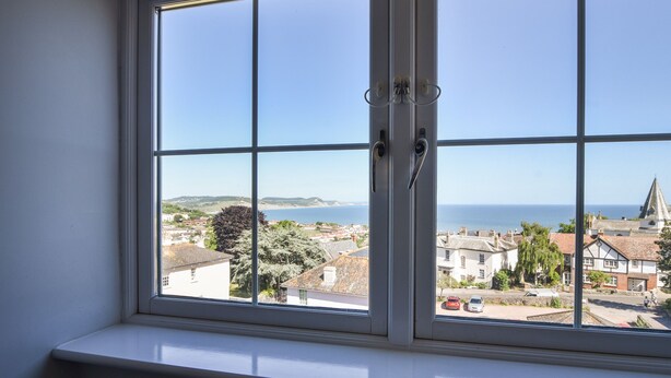 Ein Fenster mit Blick auf eine Küstenstadt, inklusive Gebäude und Meer.