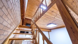 A wooden staircase leading to a loft area with skylights and exposed brick walls. - Gapyeong Acimpunggeongpension (Gapyeong)