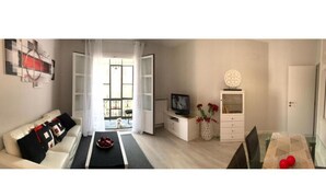 A modern living room with a sofa, coffee table, TV, and decorative items.