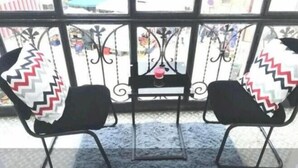 Two black chairs with patterned cushions on a balcony with a metal railing.