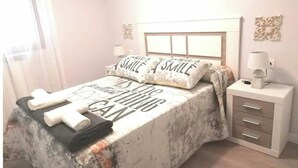 A bedroom with a bed, pillows, a bedside table, and a lamp.