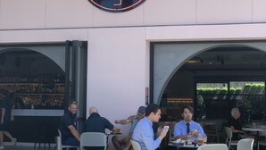 An outdoor seating area with tables and chairs, a neon flamingo sign above, and a bar visible through the entrance. - Illinois Hotel (Five Dock)