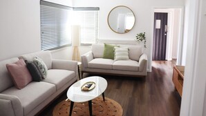 A modern living room with two sofas, a coffee table, and a large mirror. - Illinois Hotel (Five Dock)