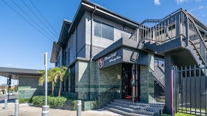 A modern hotel with a prominent entrance, a staircase, and a gated driveway. - Illinois Hotel (Five Dock)
