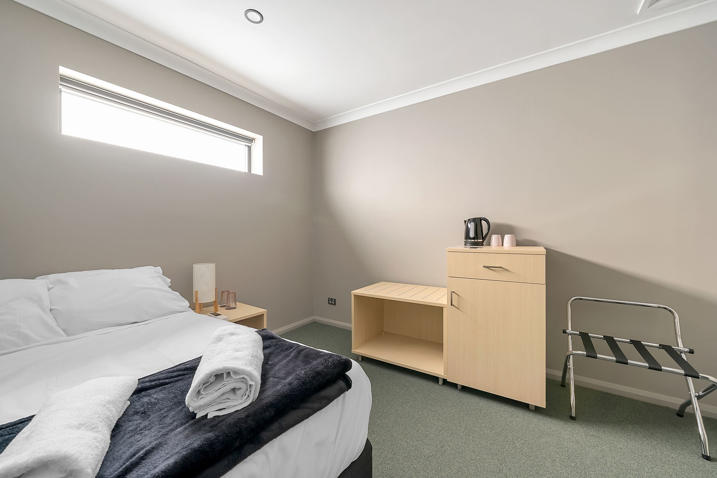 Une chambre d’hôtel avec un lit, un bureau, une chaise et une armoire.