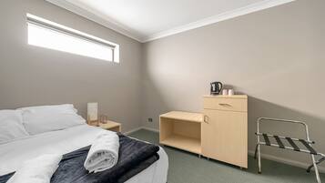 Une chambre d’hôtel avec un lit, un bureau, une chaise et une armoire.