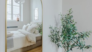 A bedroom with a bed, a mirror, and a wall-mounted plant. - Casa Lazzaro Contemporary Ground Floor Apartment (Lucca)