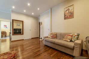 Un salon avec un canapé, un parquet et un tableau accroché au mur.
