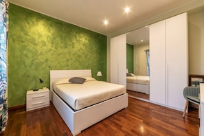 Une chambre à coucher avec un lit, une table de chevet, une commode et un miroir.