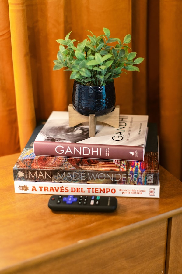 A stack of books with a remote control on a wooden surface.