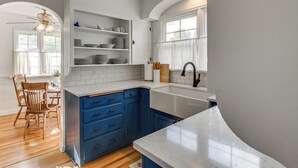 A kitchen with white cabinets, blue drawers, a white countertop, and a window with a curtain. - 6 Mi to Shoshone Falls! Charming Idaho Home (Twin Falls)