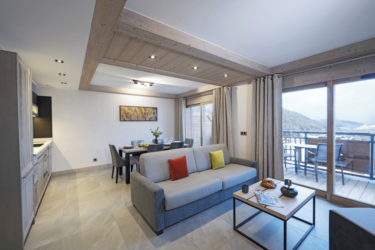 A modern living room with a sofa, dining table, and a balcony with a view.