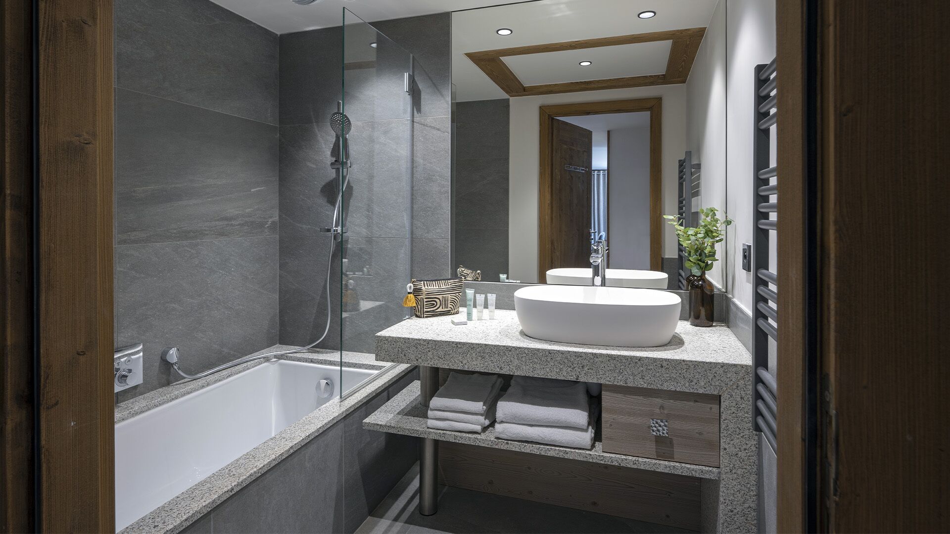 Ein modernes Badezimmer mit einer freistehenden Badewanne, einem großen Spiegel und einem Waschtisch mit Spüle und Handtuchablage.