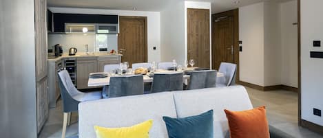 A modern dining area with a table set for four, surrounded by grey upholstered chairs.