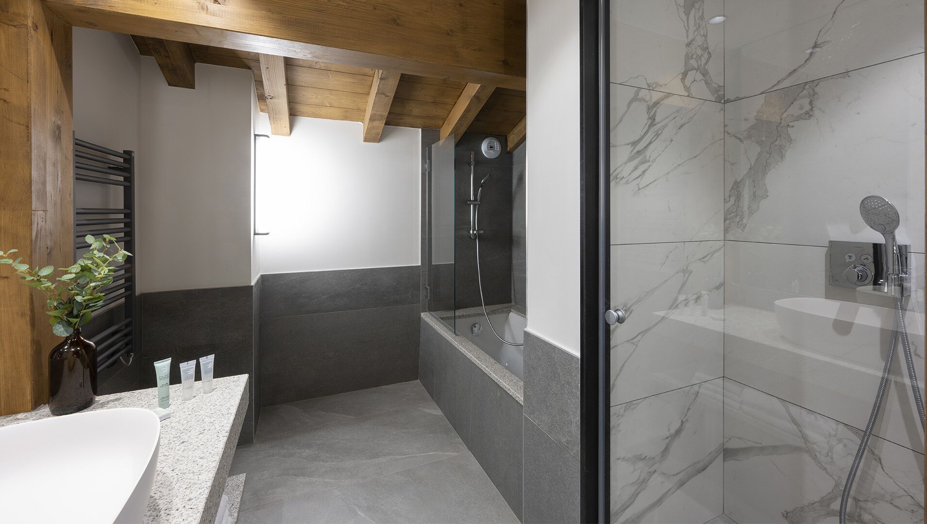 Un bagno moderno con box doccia in vetro, una vasca da bagno freestanding e zona doccia rivestita in marmo.