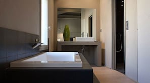 Un baño moderno con una bañera grande, un lavamanos y un espejo.