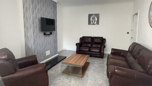 A living room with a flat-screen TV mounted on the wall, a coffee table in the center, and two leather sofas. - Regency House (Loughborough)