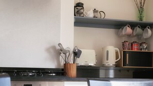 A kitchen with a stove, oven, and a dining area with chairs and a table. - Deluxe 2 bedroom upper floor apartment (Harrogate)